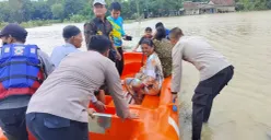 Petugas membantu masyarakat menyebrangi akibat akses jalan terendam. (Sumber: Dok. Polsek Pamarayan)