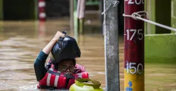 Warga berjalan melintasi banjir yang menggenangi kawasan Kebon Pala, Jakarta Timur, Jumat, 30 Januari 2026 (Sumber: Poskota/Bilal Nugraha Ginanjar)