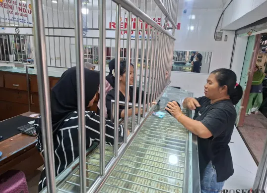 Seorang ibu rumah tangga membeli perhiasan cincin emas di Toko Emas Reni Indah (Ko Ayung) Pasar Reni Jaya Lama, Kelurahan Pondok Petir, Kecamatan Bojongsari, Kota Depok, Selasa, 15 April 2025. (Sumber: Poskota/Angga Pahlevi)