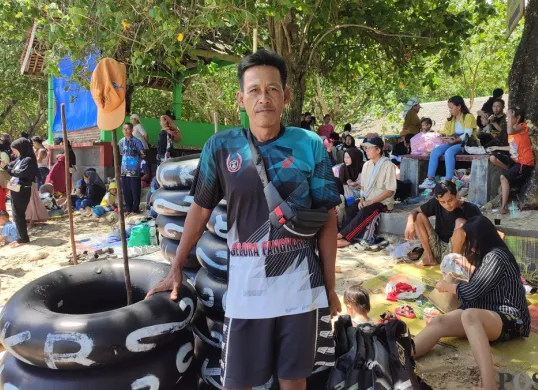Warga Desa Sukajadi, Kecamatan Carita, Pandeglang, Asmin, menghidupan keluarganya dengan membuka usaha jasa sewa ban pelampung di Pantai Carita, Selasa, 15 April 2025. (Sumber: (Poskota/Samsul Fatoni))