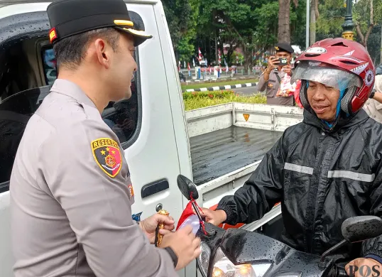 Kapolres Bogor AKBP Wikha Ardilestanto membagikan bendera merah putih kepada pengendara sepeda motor di Jalan Tegar Beriman, Cibinong, Kabupaten Bogor. (Sumber: POSKOTA | Foto: Giffar Rivana)