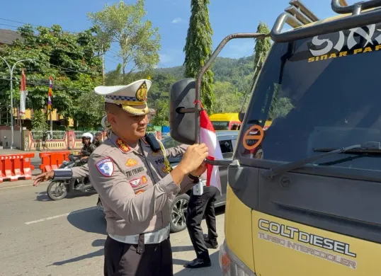 Dirlantas Polda Papua, Kombes Pol Tri Yulianto, membagikan dan langsung memasangkan bendera merah putih kepada supir truk barang di depan kantor Mapolda Papua. (Sumber: Ditlantas Polda Papua)