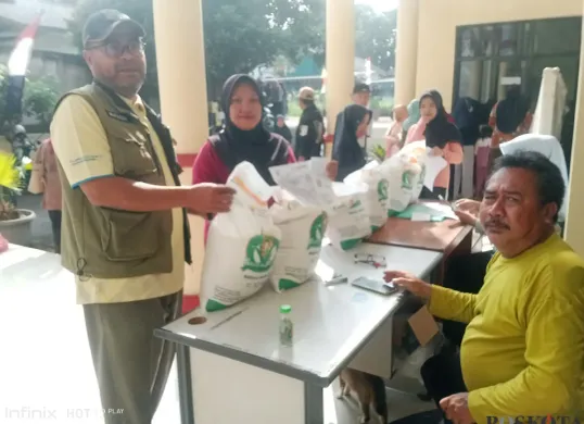 Lurah Kalibaru, Nayadih, membagikan beras bantuan pemerintah kepada warga penerima manfaat. (Sumber: Poskota/Angga Pahlevi)
