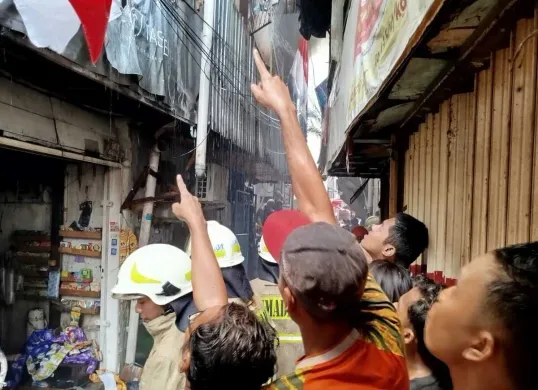 Sejumlah warga menunjuk ke salah satu bangunan rumah dalam insiden kebakaran hebat  di permukiman padat kawasan Tambora, Jakarta Barat, Rabu, 13 Agustus 2025. (Sumber: Damkar)