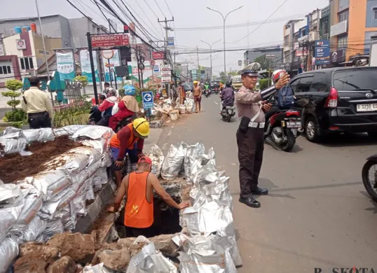 Petugas kepolisian mengatur lalu lintas di Jalan Kartini, Depok, saat proyek galian kabel menyebabkan kemacetan dan menyempitkan ruas jalan. (Sumber: Poskota/Angga Pahlevi)
