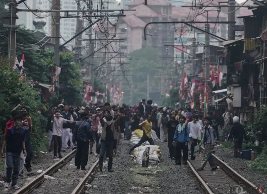 Sejumlah massa berkerumun di tengah rel kereta api, Jakarta, Senin, 25 Agustus 2025. (Sumber: Poskota/Bilal Nugraha Ginanjar)