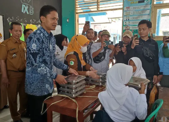 Wakil Bupati Pandeglang saat membagikan paket MBG kepada para siswa SMPN 1 Labuan. (Sumber: Poskota/Samsul Fatoni)
