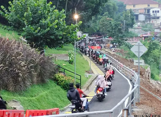 Warga melintas Jalan Saleh Danasasmita, Batutulis, Kota Bogor usai diperbaiki pasca longsor yang terjadi pada Maret lalu. (Sumber: Poskota/Giffar Rivana)
