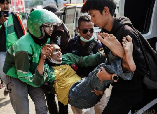 Seorang massa aksi beratribut ojek online (ojol) digotong saat demonstrasi di Satuan Brimob Polda Metro Jaya, Kecamatan Senen, Jakarta Pusat, Jumat, 29 Agustus 2025. (Sumber: Poskota/Bilal Nugraha Ginanjar)