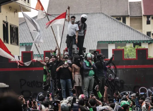 Beberapa massa aksi naik ke atas patung Komjen (Purn) Dr. H. Moehammad Jasin di Marko Brimob Polda Metro Jaya, Kecamatan Senen, Jakarta Pusat, Jumat, 29 Agustus 2025. (Sumber: Poskota/Bilal Nugraha Ginanjar)