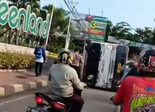 Tangkap layar truk tronton pembawa batu kerikil terbalik di Jalan Raya Parung, Kecamatan Kemang, Kabupaten Bogor.