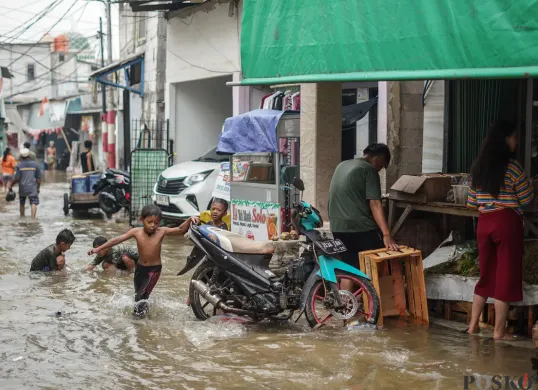 Sejumlah warga terlihat beraktifitas ditengah genangan air akibat banjir rob yang melanda kawasan Muara Angke, Jakarta Utara. (Sumber: Poskota/Bilal Nugraha Ginanjar)