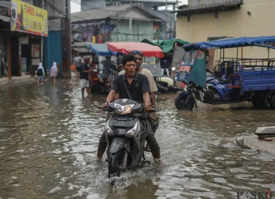 Sejumlah warga terlihat beraktifitas ditengah genangan air akibat banjir rob yang melanda kawasan Muara Angke, Jakarta Utara. (Sumber: Poskota/Bilal Nugraha Ginanjar)