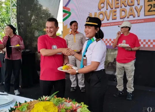 Direktur Utama LRT Jakarta, Roberto Akyuwen (kiri), memberikan potongan tumpeng kepada masinis. (Sumber: POSKOTA | Foto: Heri Effendi)