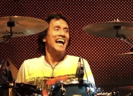 Potret Yaya Moektio saat tampil di atas panggung drummer legendaris dengan karakter kuat dan kontribusi besar bagi musik Indonesia. (Sumber: X/@Ammotsky)