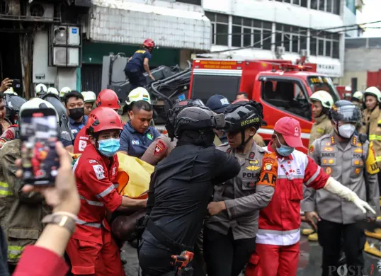 Petugas mengevakuasi jenazah dari dalam Gedung Terra Drone yang terbakar di Kemayoran, Jakarta Pusat, Selasa 9 Desember 2025. (Sumber: POSKOTA | Foto: Bilal Nugraha Ginanjar)