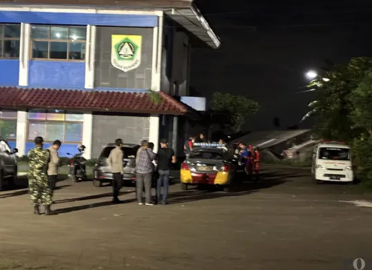 Sejumlah petugas polisi dan TNI berjaga pascapenemuan sesosok mayat pria di Gedung KNPI Cibinong, Minggu, 14 Desember 2025. (Sumber: POSKOTA | Foto: Giffar Rivana)