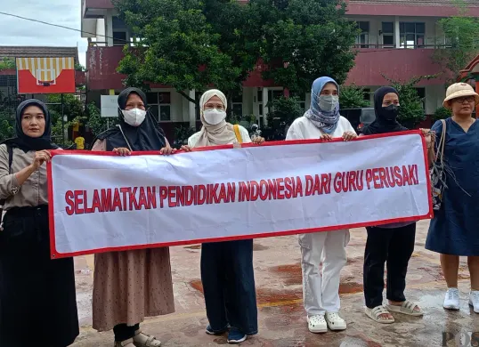 Orang tua murid di SDN Pajeleran 01 membentangkan spanduk protes tindakan diskriminatif oleh salah seorang wali kelas. (Sumber: POSKOTA | Foto: Giffar Rivana)