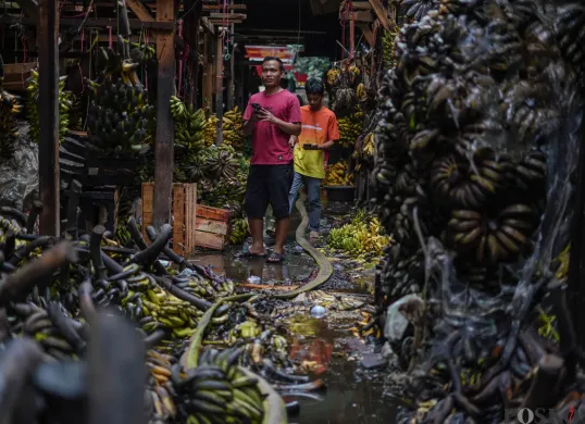 Pedagang merapihkan sisa buah-buahan yang hangus terbakar di Pasar Induk Kramat Jati, Jakarta Timur, Senin, 15 Desember 2025. (Sumber: Poskota/Bilal Nugraha Ginanjar)