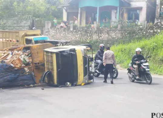 Sebuah unit truk pengangkut sampah nampak terguling di kawasan Jalan Raya Cipatat, Senin 15 Desember 2025. (Sumber: Poskota/Gatot Poedji Utomo)
