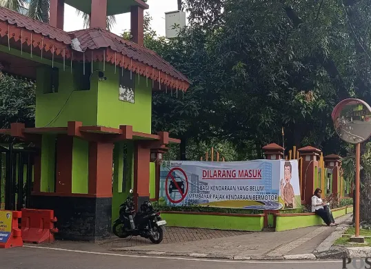 Pemkot Bekasi memasang spanduk sosialisasi larangan masuk kantor bagi kendaraan yang belum membayar pajak di pintu masuk. (Sumber: POSKOTA | Foto: Nurpini Aulia Rapika)