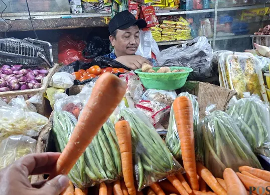 Pedagang sayuran melayani pembeli di Pasar Depok Jaya. Wortel jadi salah satu komoditas yang harganya naik jelang Natal 2025 dan Tahun Baru 2026. (Sumber: POSKOTA | Foto: Angga Pahlevi)