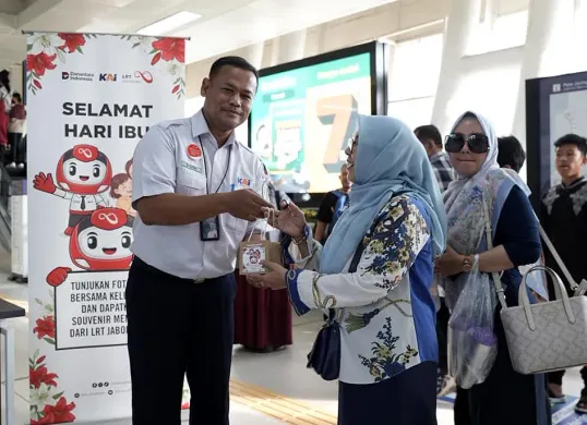 Manager Passenger Marketing and Sales, Asep Dodi Rahmat Suhartono (kiri), memberikan tanaman hias kepada pengguna LRT Jabodebek di Stasiun Dukuh Atas, Senin, 22 Desember 2025. (Sumber: PR LRT Jabodebek)