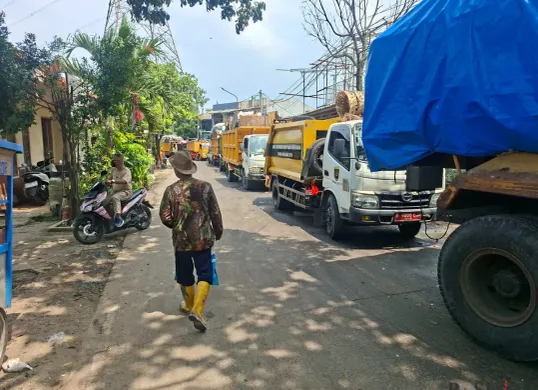 Antrean kendaraan pengangkut sampah mengular di Jalan TPA Jalan Baru, Cipayung, Kota Depok, Selasa, 23 Desember 2025, akibat keterbatasan akses masuk dan pemeliharaan fasilitas di TPA Cipayung. (Sumber: Poskota/Angga Pahlevi)