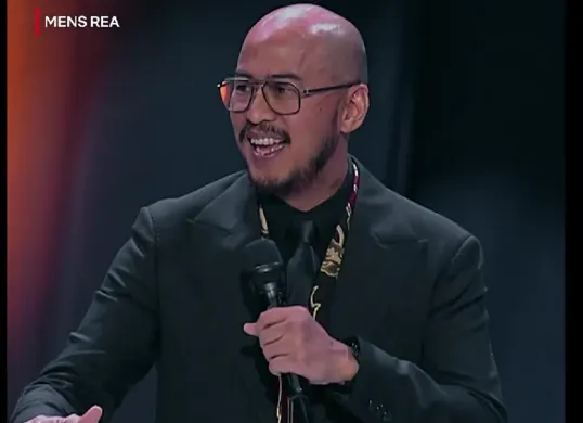 Pandji Pragiwaksono saat membawakan special stand-up comedy Mens Rea, sebuah pertunjukan tanpa sensor yang menggabungkan humor dan refleksi kritis tentang politik dan niat di balik kekuasaan. (Sumber: Dok/Netflix)