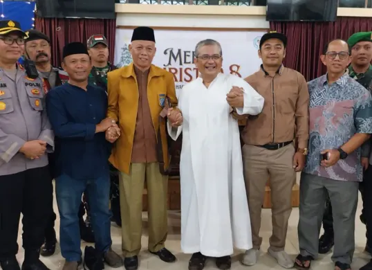 Romo Rudi (tengah baju putih) bersama warga dan perangkat pemerintah didampingi Kapolsek Beji Kompol Josman Harianja menjaga kebersamaan di perayaan Natal di Wisma Sahabat Yesus. (Sumber: Istimewa)