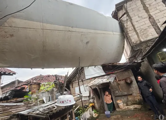 Penampakan bangkai sayap pesawat timpa rumah warga di wilayah Kemang, Kabupaten Bogor karena angin puting beliung, Senin 29 Desember 2025. (Sumber: Poskota/Giffar Rivana)