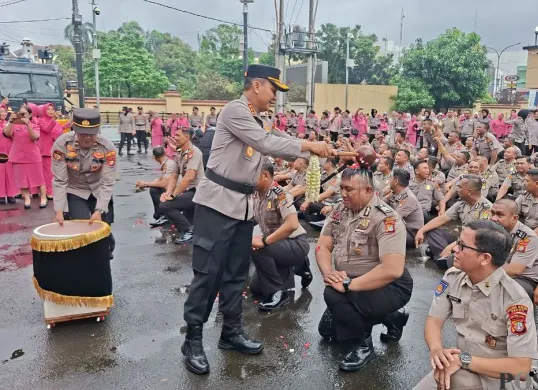 Kapolres Metro Depok, Kombes Pol Abdul Waras melakukan tradisi siram air kembang kepada personel yang naik pangkat di Mapolres Metro Depok, Rabu, 31 Desember 2025. (Sumber: Poskota/Angga Pahlevi)