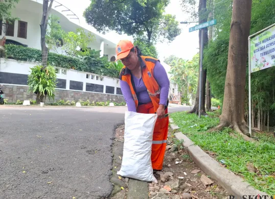 Yenny Lies Damona, petugas PPSU Kelurahan Pulo, sedang memadatkan dedaunan kering di dalam karung di Kelurahan Pulo, Kebayoran Baru, Jakarta Selatan, Sabtu, 1 Februari 2024. (Sumber: Poskota/Angga Pahlevi)