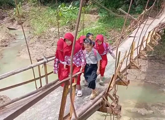 Sejumlah anak-anak SD di Desa Nanggala, Kecamatan Cikeusik, Kabupaten Pandeglang, saat melintas jembatan gantung yang nyaris putus. (Sumber: Dok. Warga)