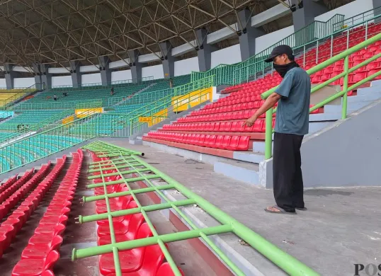 Salah satu pekerja menunjukkan salah satu pagar tribun Stadion Patriot Chandrabaga, mengalami kerusakan, Senin, 17 Februari 2025. (Sumber: Poskota/Ihsan Fahmi)