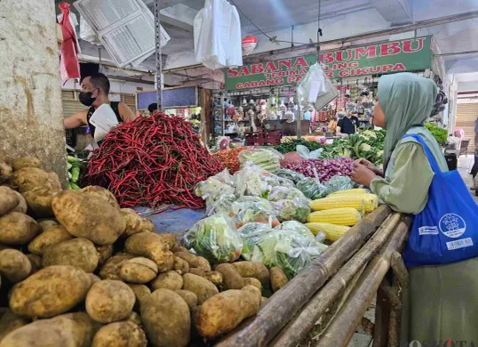 Aliudin, pedagang sayuran di Pasar Gudang Tigaraksa saat sedang melayani konsumen, Selasa, 18 Februari 2025. Harga kentang di pasar ini mengalami kenaikan. (Sumber: Poskota/Veronica Prasetio)