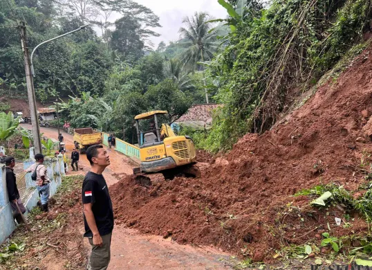 Petugas BPBD KBB dan warga berjibaku membersihkan material longsor di Jalan Raya Kampung Tugu RW 14 Desa Ciharashas, Kecamatan Cipeundeuy, Rabu 26 Februari 2025. (Sumber: Poskota/Gatot Poedji Utomo)