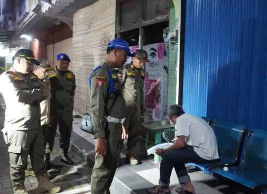 Petugas Satpol PP saat memberikan surat edaran tentang jam operasional usaha di Kabupaten Tangerang selama bulan Ramadhan. (Sumber: Poskota/Veronica Prasetio)