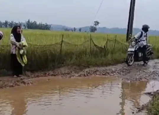 Seorang guru menangis di tepi Jalan Cimoyan, Kecamatan Patia, Pandeglang, yang kondisinya rusak parah. (Sumber: Dok. Warga)