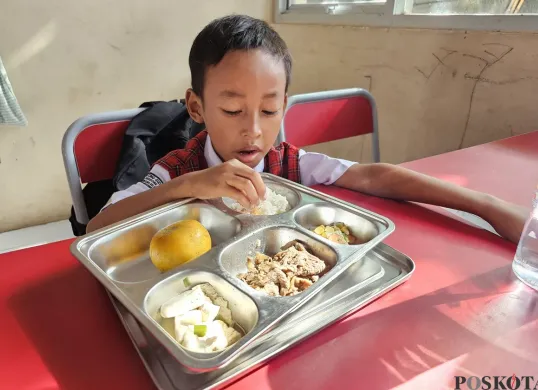 Gibran Hafiz Nurdiansyah, 7 tahun, siswa SDN Lengkong Gudang, Kota Tangsel saat menyantap menu MBG. (Sumber: Poskota/Veronica Prasetio)