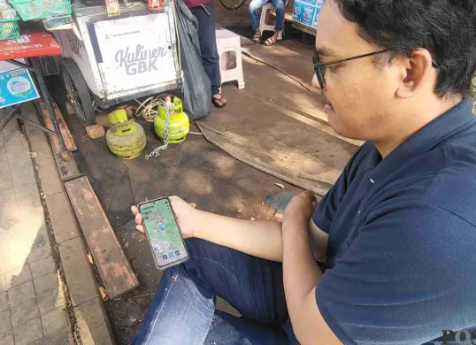 Hikari, 32 tahun, saat tengah membuka aplikasi 'koin jagat' untuk mencari titik letak di kawasan GBK, Senayan, Jakarta Pusat. (Sumber: Poskota/Pandi Ramedhan)