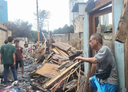 Iyang, 55 tahun, salah satu warga yang rumahnya terdampak kebakaran di Kemayoran, Jakarta Pusat, sedang melihat kondisi terkini rumahnya yang sudah hangus, Selasa 21 Januari 2025. (Sumber: Poskota/Pandi Ramedhan)