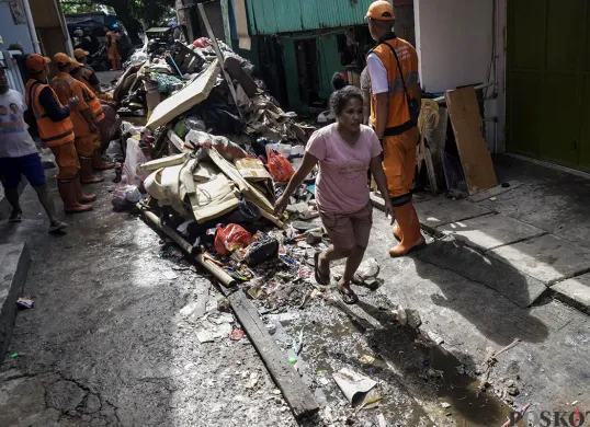 Petugas PPSU Kelurahan Kapuk, mengangkut tumpukan sisa sampah yang terbawa arus air banjir di Jalan Kapuk Bongkaran, Cengkareng, Jakarta Barat, Kamis, 30 Januari 2025. (Sumber: Poskota/ Bilal Nugraha Ginanjar)