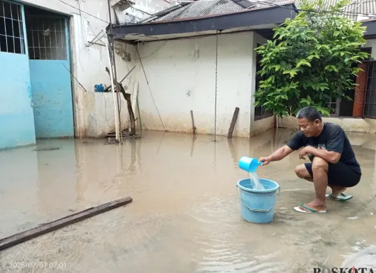 Himin, 52 tahun, Warga Kampung Lebak, Teluk Pucung, Kota Bekasi, berusaha membuang genangan air yang ada di luar rumahnya akibat banjir kiriman dari Bogor, Senin, 7 Juli 2025. (Sumber: Poskota/Nurpini Aulia Rapika)