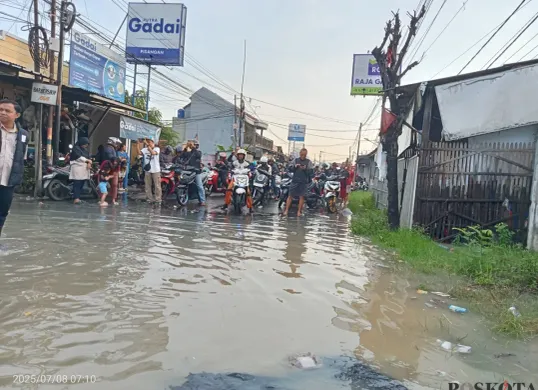 Jalan Raya Pisangan, Desa Satria Mekar, Kecamatan Tambun Utara, Kabupaten Bekasi, lumpuh total usai terendam banjir setinggi 50 sentimeter. Selasa, 8 Juli 2025. (Sumber: Poskota/Nurpini Aulia Rapika)