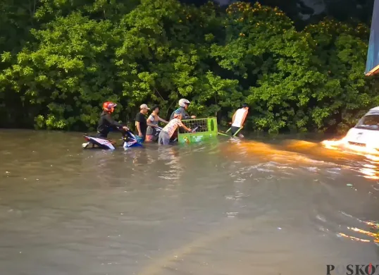 Warga di Kembangan Selatan, Kembangan, Jakbar, buka jasa sewa gerobak untuk pengendara motor yang mau menyebrangi banjir di ruas Jalan Ring Road, Selasa 8 Juli 2025. (Sumber: POSKOTA | Foto: Pandi Ramedhan)
