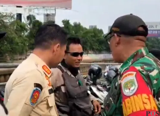 Seorang juru parkir liar di kawasan Mall Taman Anggrek Jakbar, ditegur petugas karena memakai baret TNI saat razia parkir liar. (Sumber: POSKOTA | Foto: Pandi Ramedhan)