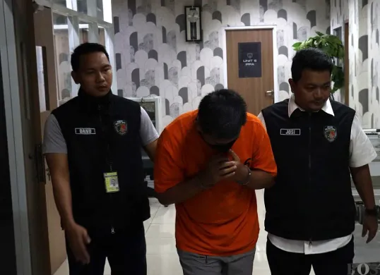 Anggota Polresta Bandara Soetta menggiring IM (tengah), terduga kasus pelecehan seksual yang dialami seorang penumpang anak di bawah umur dalam penerbangan pesawat Citilink rute Denpasar-Jakarta. (Sumber: POSKOTA | Foto: Ali Mansur)