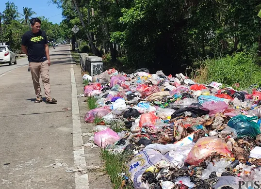 Warga mengamati tumpukan sampah di Jalan Raya Sobang-Ciseket, Desa Mekarsari, Kecamatan Panimbang, Pandeglang. (Sumber: POSKOTA | Foto: Samsul Fatoni)
