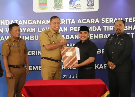 Bupati Bekasi Ade Kuswara Kunang dan Walikota Bekasi Tri Adhianto menandatangani berita acara serah terima aset dan layanan Perumda Tirta Bhagasasi Cabang Rawalumbu dan Cabang Pembantu Setia Mekar, di Pemkot Bekasi. (Sumber: Dok. Pemkab Bekasi)
